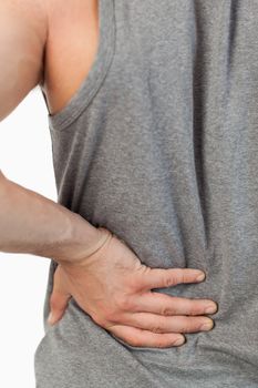 Male hands touching own back against a white background