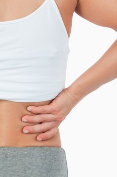 Close up of female with back pain against a white background