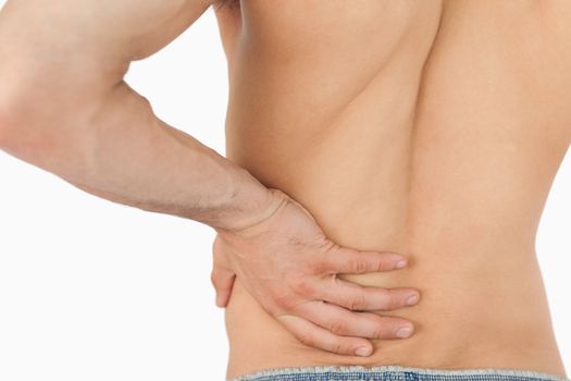 Young man experiencing back pain against a white background