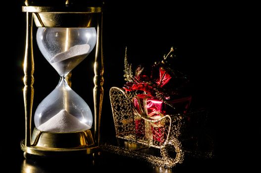 Christmas gift on sleigh and hourglass on black background.  Concept showing time running out for Christmas shopping.