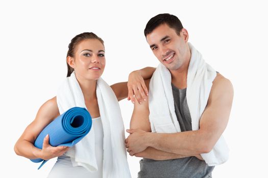 Fit couple going to practice yoga against a white background