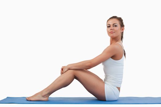 Woman sitting on a foam mat against a white background