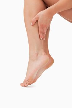 Close up of a feminine hand touching legs against a white background