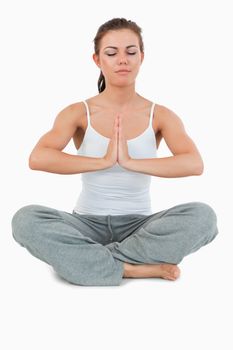 Portrait of a young woman in the Sukhasana position against a white background