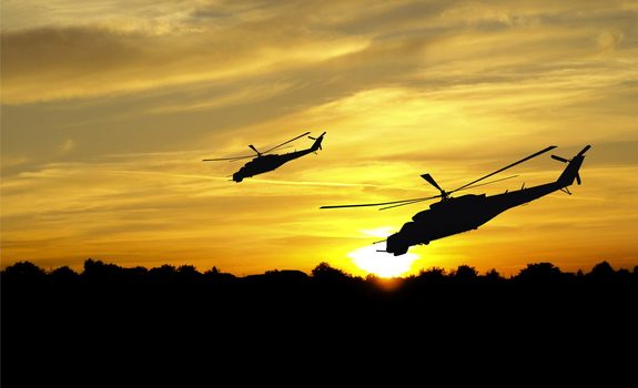 Flying helicopter silhouettes on sunset background