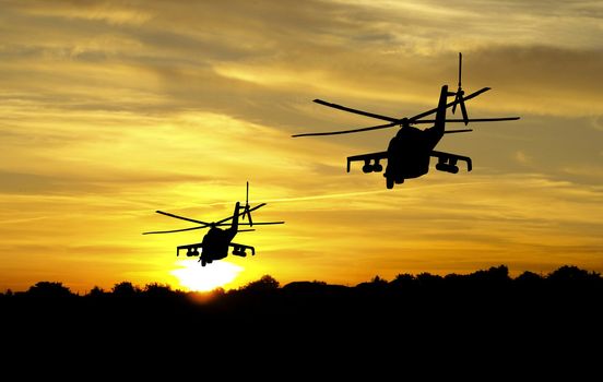 Flying helicopter silhouettes on sunset background