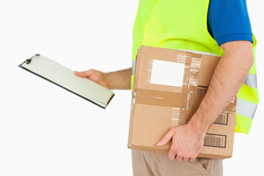 Side view of young delivery man with delivery note and parcel against a white background