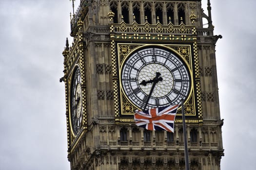 Clock on Big Ben with the British flag flying - this is one of the four clock faces that surround the tower on the Houses of Parliament, London, England