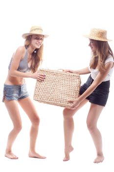 Two girls in straw hats with a straw suitcase, studio photography