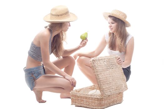 Two girls in straw hats with a straw suitcase, studio photography