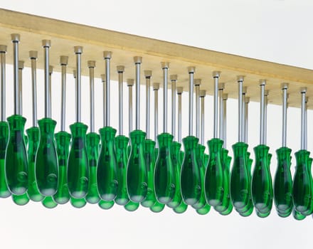 A large set of green screwdrivers in a row