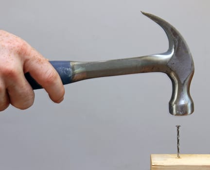 A person hammering a nail into a piece of wood.
