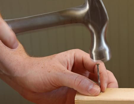 A person hammering a nail into a piece of wood.
