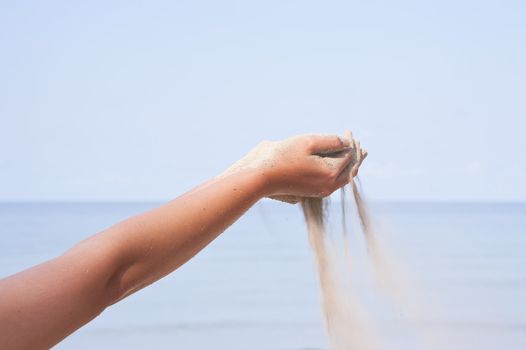 Hand with sand on sea background