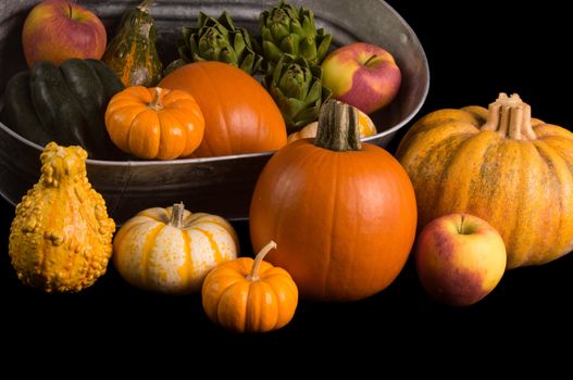 Cornucopia of fresh pumpkins, squash, apples and pomegranet isolated on black background