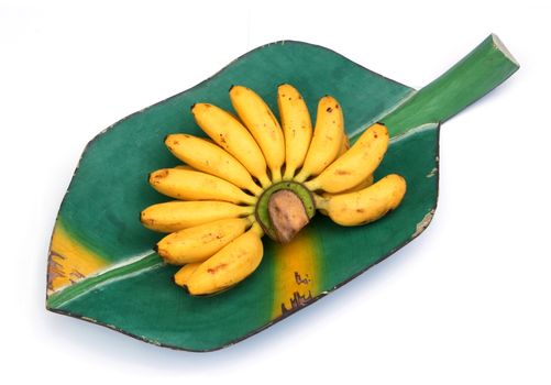 Bunch of bananas on a banana leaf, wooden tray isolated over white background 
