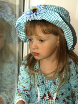 Thoughtful  little girl looking through the window. Portrait