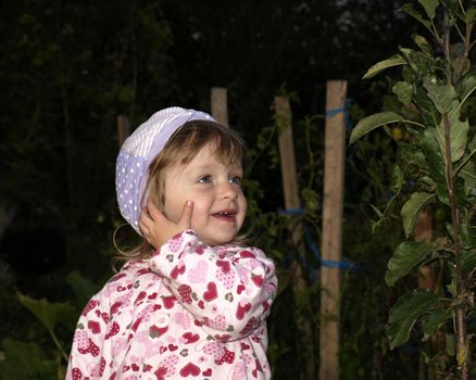 Nice smiling little girl looking at the plant