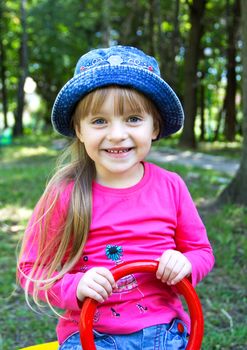 Cute smiling little girl playing at the  see-saw on playground