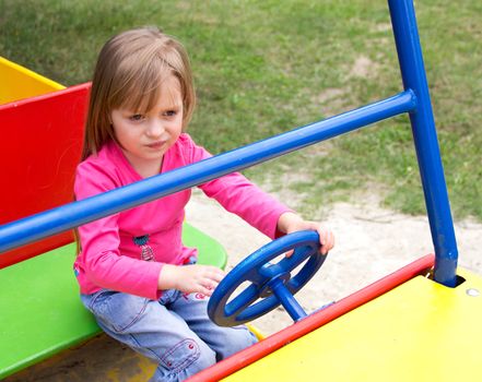 Cute smiling little girl playing on playground car