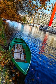 A green boat on a canal in Amsterdam during the autumn.