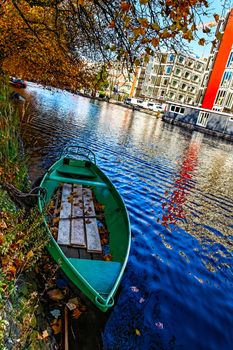 A green boat on a canal in Amsterdam during the autumn.