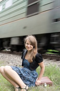 The girl is sitting on a suitcase in the background speeding train