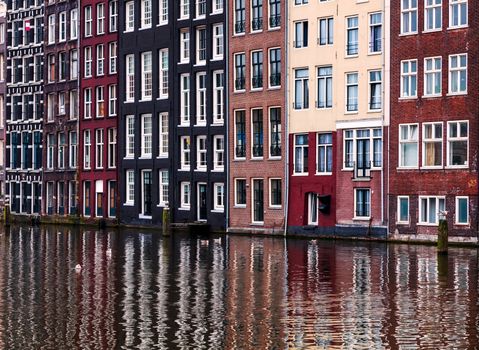 Typical colorful facades of houses and their reflections in a water canal in Amsterdam.