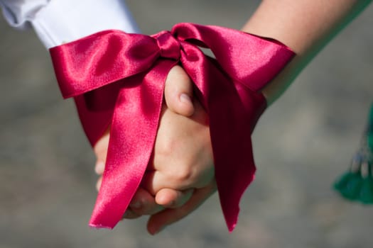 Wedding ceremony - Hands of women and men are associated with red ribbon