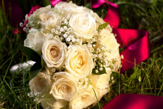 Bridal bouquet of white roses lay in the grass