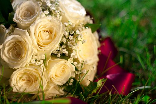 Bridal bouquet of white roses lay in the grass