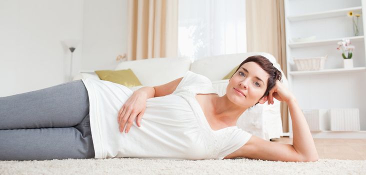 Woman lying on a carpet in her living room