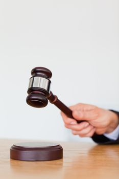 Portrait of a hand knocking a gavel against a white background