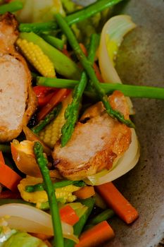 low fat asian vegetable dish with chicken in a wok on wooden table