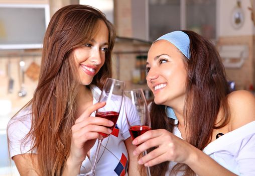 Happy women drinks red wine in the kitchen and talk about
