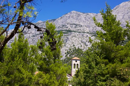 Church in old village of Tucepi below towering mountains of Biakovo nature park on Makarska Riviera in Dalmatia, Croatia