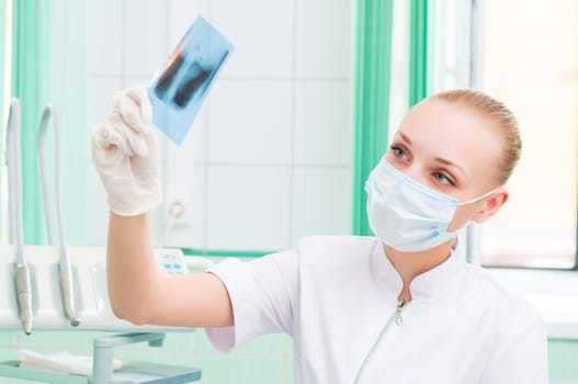 woman doctor in protective mask looking at x-ray, protection of health