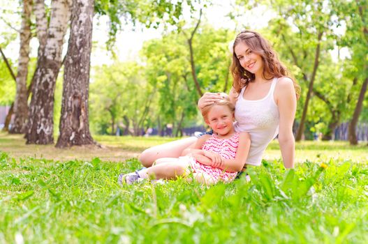 mother and daughter sitting together on the grass, and spend time with family