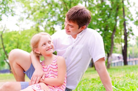 Father and daughter sitting together on the grass, and spend time with family