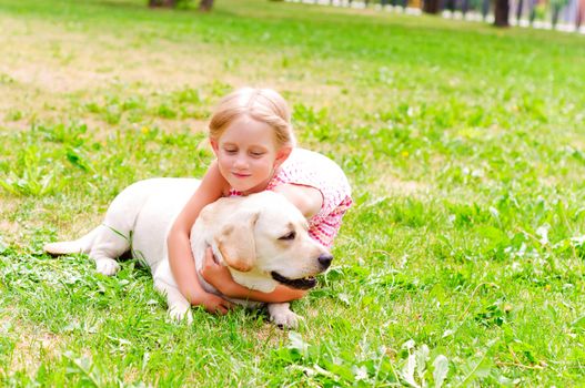 girl and she lablador, hugging in the park lying on the grass