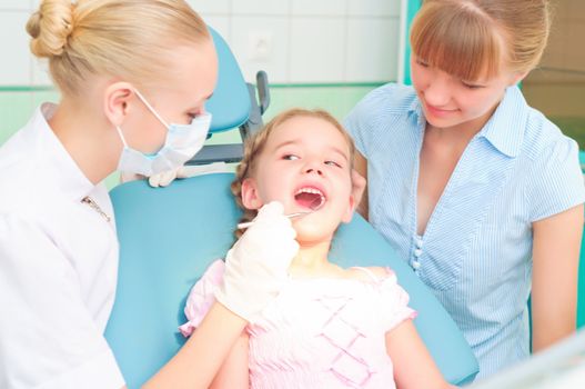 female dentists examines a child, my mother was sitting beside him and soothes baby