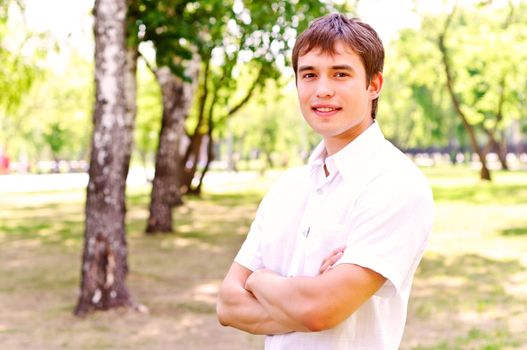 Portrait of man outside in park, crossed his arms