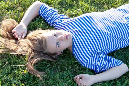 beautiful girl in the shirt on the grass outdoors shooting