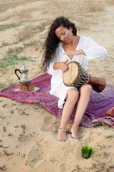 Female playing a djembe in an African setting