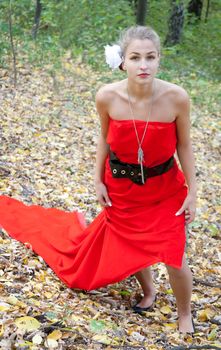 Pretty girl in red dress in the autumn in the woods shooting outdoors