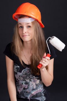 girl in a helmet with a roller to paint in his hand