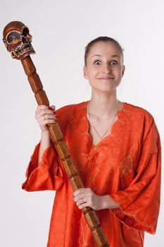 Girl in orange dress on a light background with a staff