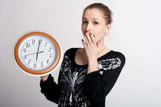sleeping girl on a white background with a big clock in the hands of which 6 am