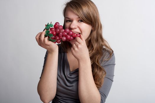 girl on a light background is eating grapes