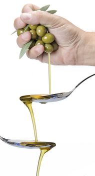 A hanful of olives dropping olive oil into a spoon